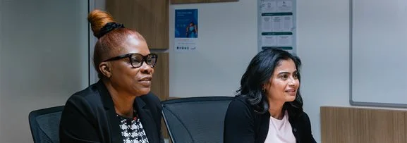 Two female staff engaging in a meeting in the workplace.