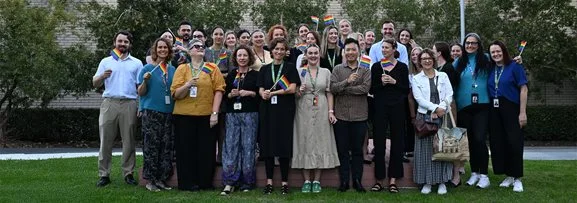Mental Health Commission staff standing for a group photo, holding LGBTI+ flags.