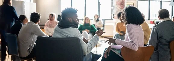 People sitting in a circle having a group discussion as part of their training.
